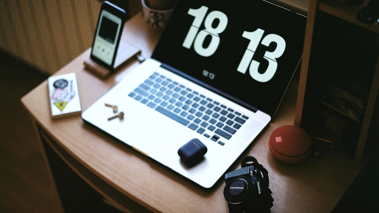 Laptop, smartphone, camera and earbuds on a desk