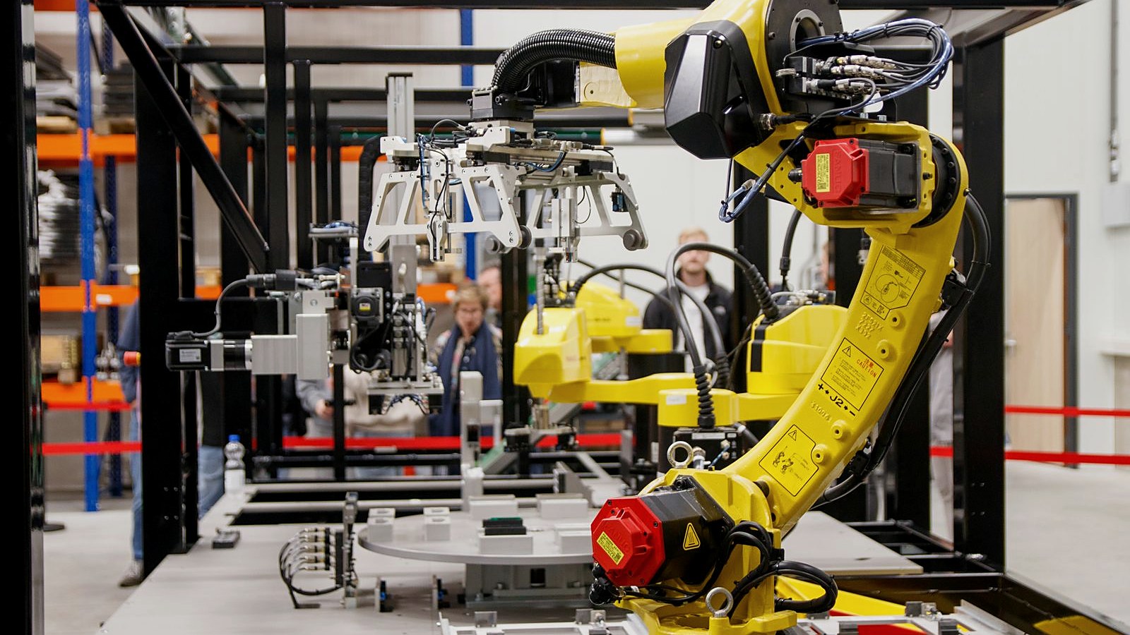 Automated production cell with industrial robot arm assembling electronic assemblies